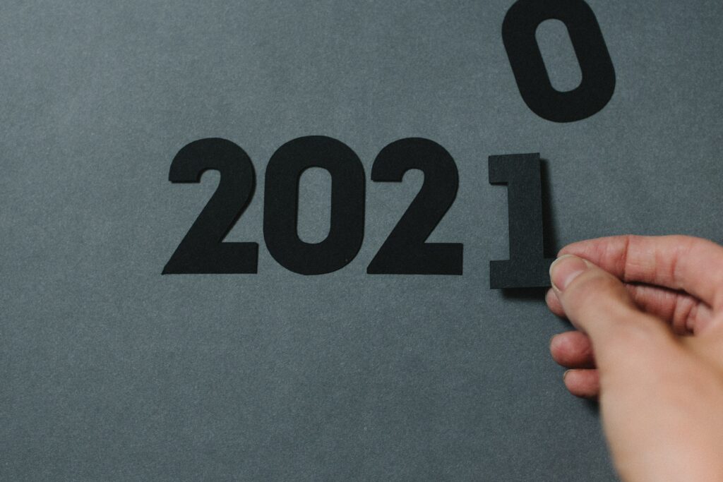Planning for the year ahead. The numbers 202 with a hand putting a 'one' to replace the 'zero' visible off to the side, and make the numbers read 2021.