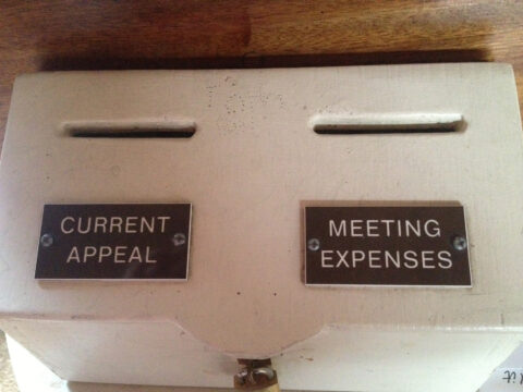photo of a collection box, two slots one saying current appeal, the other meeting expenses